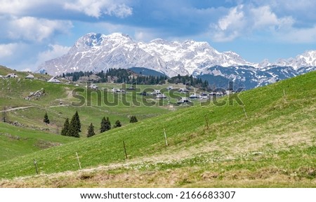 A picture of the landscape of Velika Planina, or Big Pasture Plateau, and its herder huts, with the Kamnik–Savinja Alps on the background. Royalty-Free Stock Photo #2166683307