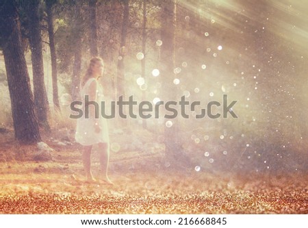 surreal blurred background of young woman stands in forest. abstract and dreamy concept. image is textured