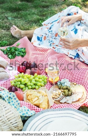 Cropped picture of a girl sitting on a grass on nature. Concept of having picnic in a city park during summer weekends.