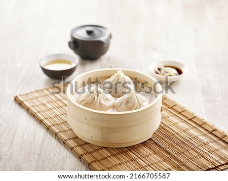 Steamed Xiao Long Bao served in a wooden bowl isolated on mat side view on grey background Royalty-Free Stock Photo #2166705587