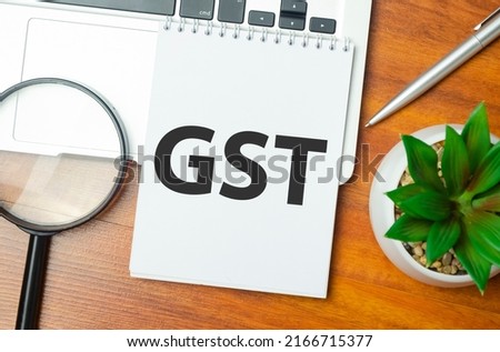 GST word on notepad and laptop on wooden background
