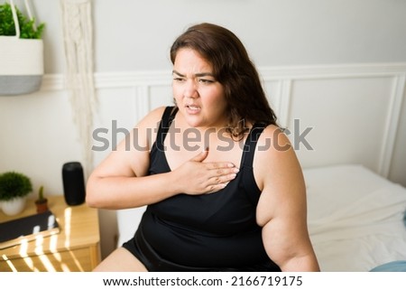 Unhealthy obese woman putting a hand in her chest and having heart problems or suffering from tachycardia Royalty-Free Stock Photo #2166719175