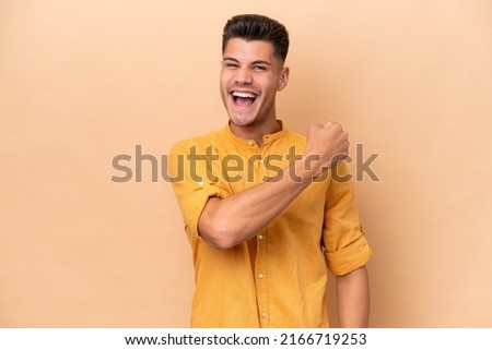 Young caucasian man isolated on beige background celebrating a victory Royalty-Free Stock Photo #2166719253