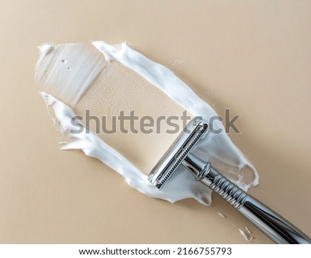Vintage safety metal razor, with smeared shaving foam on a beige background. copy space and flatlay. Royalty-Free Stock Photo #2166755793