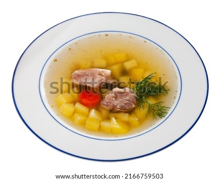 Hearty homemade soup with pork meat on bone and vegetables served with greens. Isolated on white background