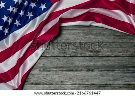 AMERICAN FLAG WITH CREASES AND FOLDS ON OLD WOODEN PLANKS BACKGROUND. MEMORIAL DAY CONCEPT AND INDEPENDENCE DAY CELEBRATION IN US. COPY SPACE.
