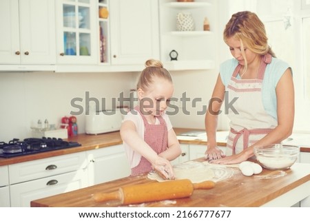 Doing some bonding over baking. Cute little girl baking in the kitchen with her mom.
