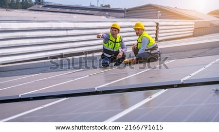 Engineers walking on roof inspect and check solar cell panel by hold equipment box and radio communication ,solar cell is smart grid ecology energy sunlight alternative power factory concept.