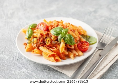 Pasta Penne Bolognese in white plate on light background. Bolognese sauce is classic italian cuisine dish. Popular italian food. Royalty-Free Stock Photo #2166798613