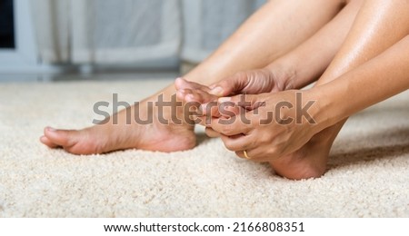 Foot pain, Asian woman holds her toe injury feeling pain her foot at home, female suffering from feet ache use hand massage relax muscle from toe in house interior, Healthcare problems medical concept