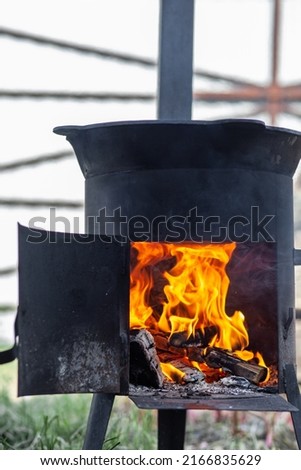 Cooking food or pilaf in a cauldron on fire. Cooking in cauldron on open fire in nature. Bowler on bonfire in forest. Close-up fire flame. Copy space.