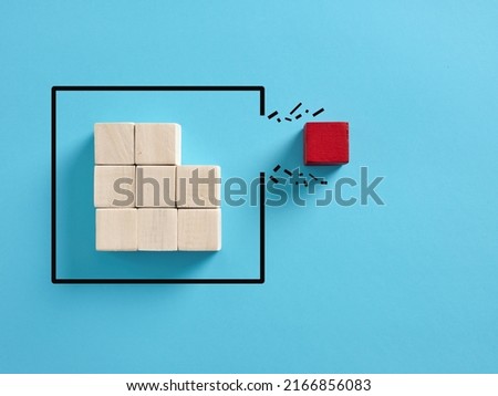 Concept of overcoming barriers, individuality and independence in business. Red wooden cube breaking through the obstacle. Royalty-Free Stock Photo #2166856083