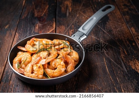 Fried with butter and garlic prawns shrimps in a skillet. Wooden background. Top view.