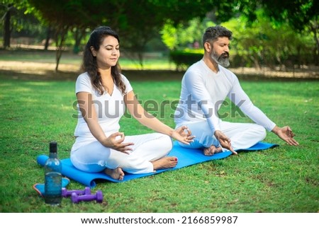 Two indian male and female person do yoga mediation exercise together in the summer  park outdoor. Healthy lifestyle, Sports and workout concept, Royalty-Free Stock Photo #2166859987