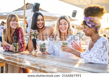 Group of young and attractive women having fun and drink at chiringuito, beautiful girls on vacation sitting at chiringuito table on sunset and having fun at summer party Royalty-Free Stock Photo #2166867491