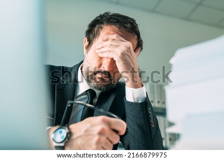 Overworked businessman at office desk, tired fatigued business owner in stressful situation, selective focus Royalty-Free Stock Photo #2166879975