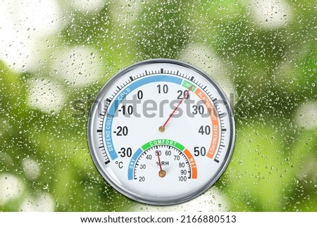 Mechanical hygrometer with thermometer on glass with water drops Royalty-Free Stock Photo #2166880513
