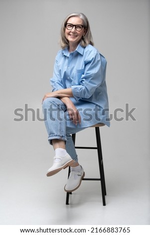 Maturity and style of adult woman. Fashionable mature female sitting on a chair sitting on a chair Royalty-Free Stock Photo #2166883765