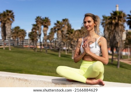 Beautiful young woman practising yoga outside. Fit woman doing yoga stretching exercises