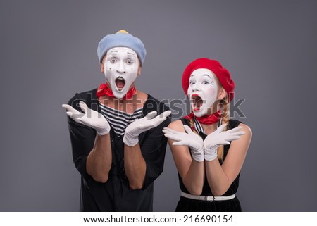 Waist-up portrait of funny mime couple with white faces solemnly singing and waving their hands isolated on grey background with copy place Royalty-Free Stock Photo #216690154