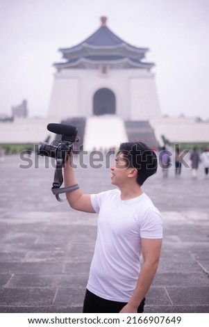 Asian guy raise his camera taking picture in chinese temple area
