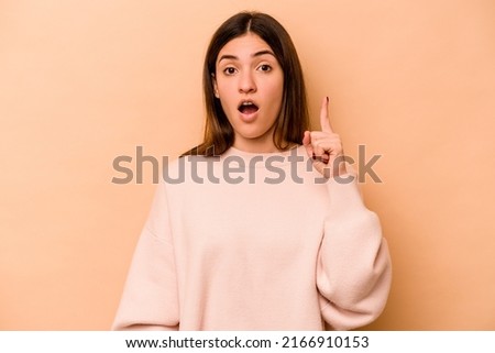 Young hispanic woman isolated on beige background having some great idea, concept of creativity.