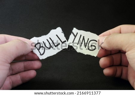 Fight and stop bullying concept. Hand tearing paper with word bullying in dark black background. Royalty-Free Stock Photo #2166911377