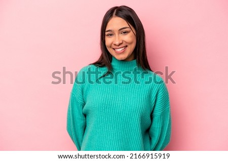 Young hispanic woman isolated on pink background happy, smiling and cheerful.