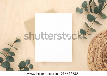 Blank greeting card, invitation mockup. Eucalyptus branches plant on wooden table background. Flat lay, top view. Copy space. Canvas mock up. Modern Minimal business brand template. Soft shadow.