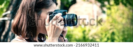 Young woman with a camera taking pictures outdoor. Banner design