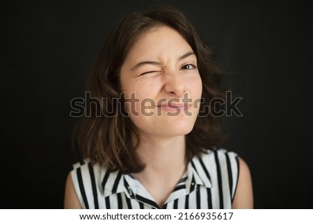 Portrait of happy tennage girl making faces over black background.