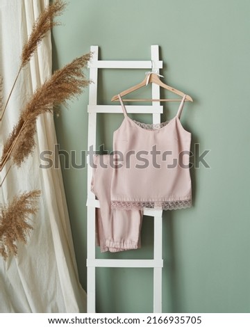                  Beautiful pink nightwear pajamas hang on a hanger. The concept of clothes for sleep and relaxation.               Royalty-Free Stock Photo #2166935705