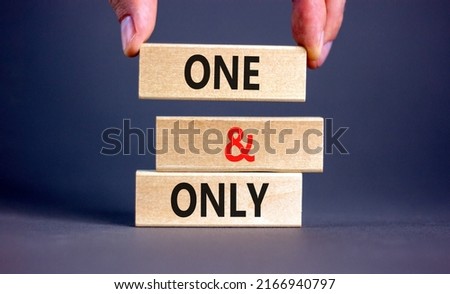 One and only symbol. Concept words One and only on wooden blocks on a beautiful grey table grey background. Businessman hand. Business, motivational One and only concept. Copy space.