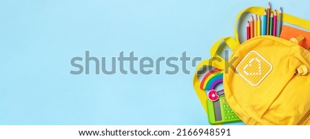 Back to school, education concept Yellow backpack with school supplies - notebook, pens, eraser rainbow, numbers isolated on blue background Top view Copy space Flat lay composition Banner