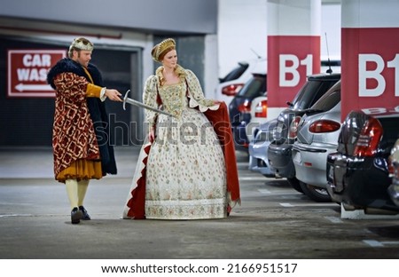 Stand back mlady, Ill deal with these creatures. A king and queen in a parking garage viewing cars suspiciously.