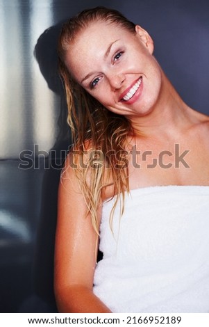 After bath - Cute woman wrapped in a towel and smiling. Portrait of a cute smiling woman wrapped in bath towel against a dark background.
