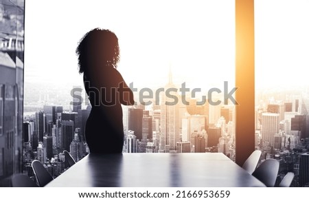 Shes got big plans to run the city. Silhouetted shot of a young businesswoman looking at a cityscape from an office window. Royalty-Free Stock Photo #2166953659