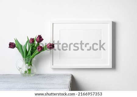 Blank landscape art frame mockup with spring tulips flowers over white wall