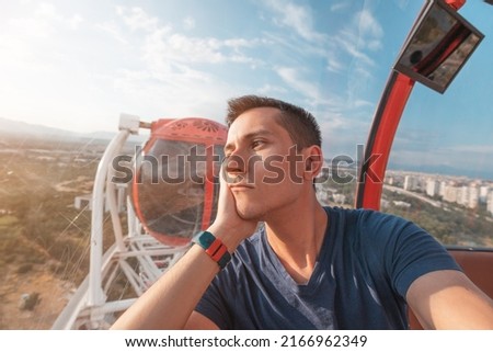 Depressed and sad young man taking selfie while riding ferris wheel in amusement luna park. Loneliness and depression concept Royalty-Free Stock Photo #2166962349