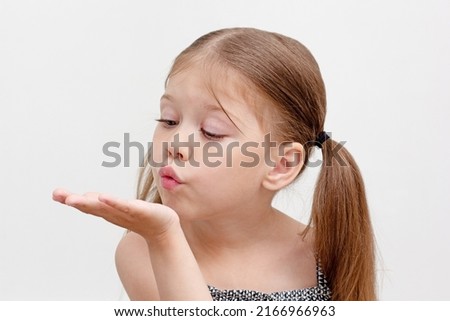 Caucasian little girl of 6 years blowing on palm as breathing exercise in speech therapy. Concept dysarthria, logopedics Royalty-Free Stock Photo #2166966963