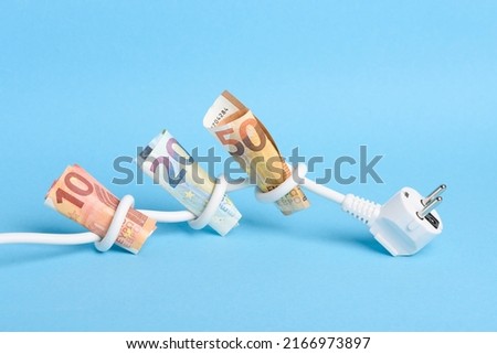 Euro bills tied in knots in power electrical power cable on blue background. Concept of expensive electricity costs in Europe and rise in energy bill prices. Royalty-Free Stock Photo #2166973897