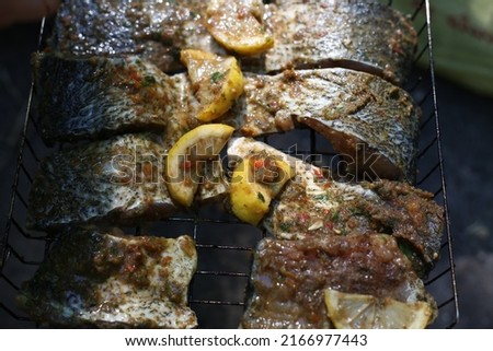Marinated fish is fried on a grill. Fish fillet in sauce with lemon for frying on the grill