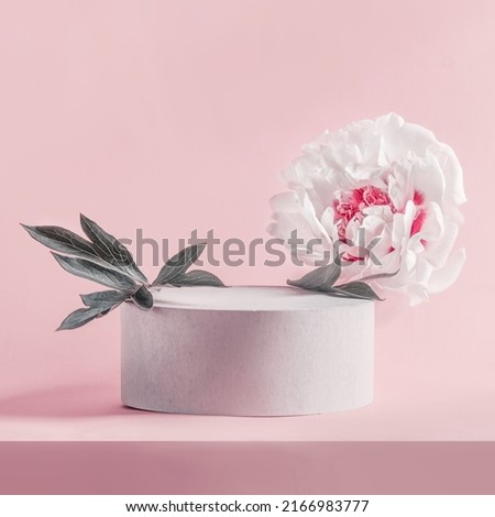 Product podium with white peony bloom and leaves at pink background. Showcase for beauty product placement. Modern display case. Front view with copy space.