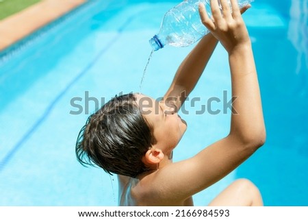 Heat stroke.heat wave. Cool off in the summer heat wave in the pool. young man splashing a bottle of water on his face. Concept of high temperatures in summer.