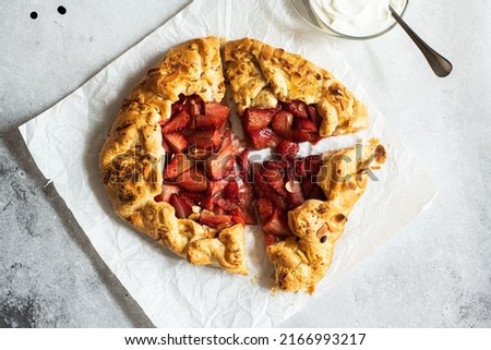Strawberry summer galette with puf pastry and almond flakes with cream. Top view.