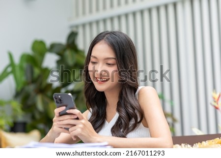 Happy asian young woman smile using smartphone surfing internet and enjoy with social media or online shopping at home. Modern wellness life of cute female looking at mobile phone fun and happiness