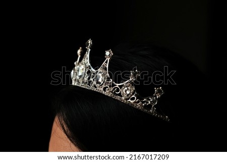 Crown on young woman's head on dark background