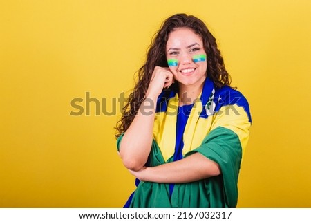 Woman soccer fan, fan of brazil, looking at camera with hand on chin. interactive photo.