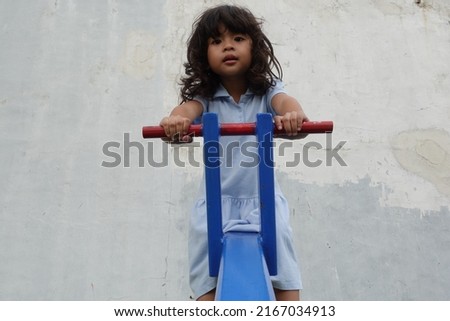 toddler girl playing seesaw in the park