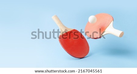 Red  ping pong table tennis paddle rackets with ball on blue background. Summer sport activity concept. Flying Royalty-Free Stock Photo #2167045561